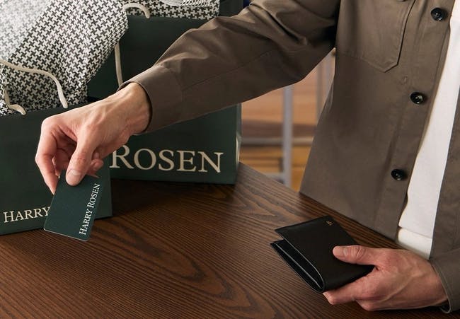 male hands holding gift card abd wallet over harry rosen cash desk