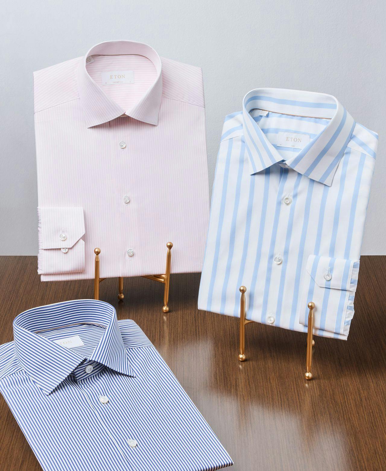 two dress shirts displayed on standand one on table