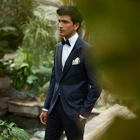 male model outside with hand in pocket wearing suit and bow tie