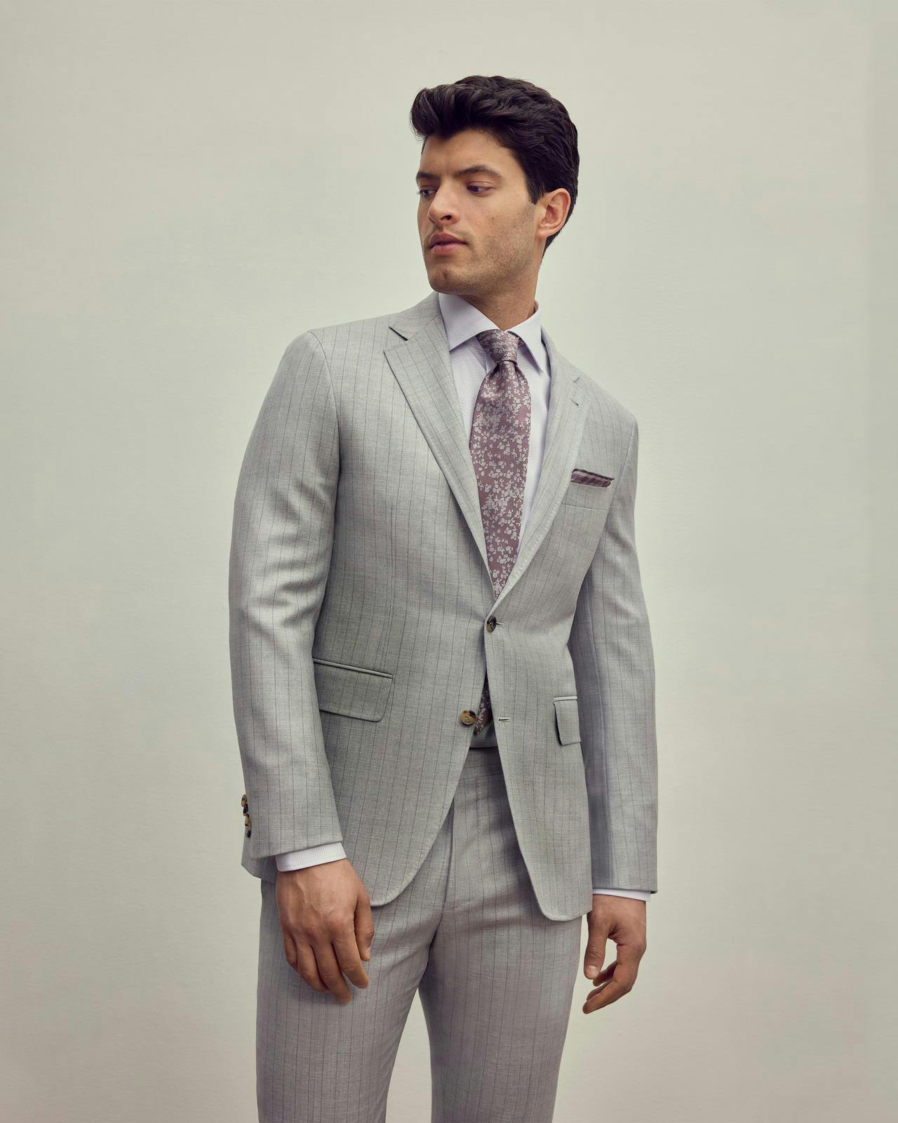 un modèle masculin dans un costume gris clair et une cravate rose