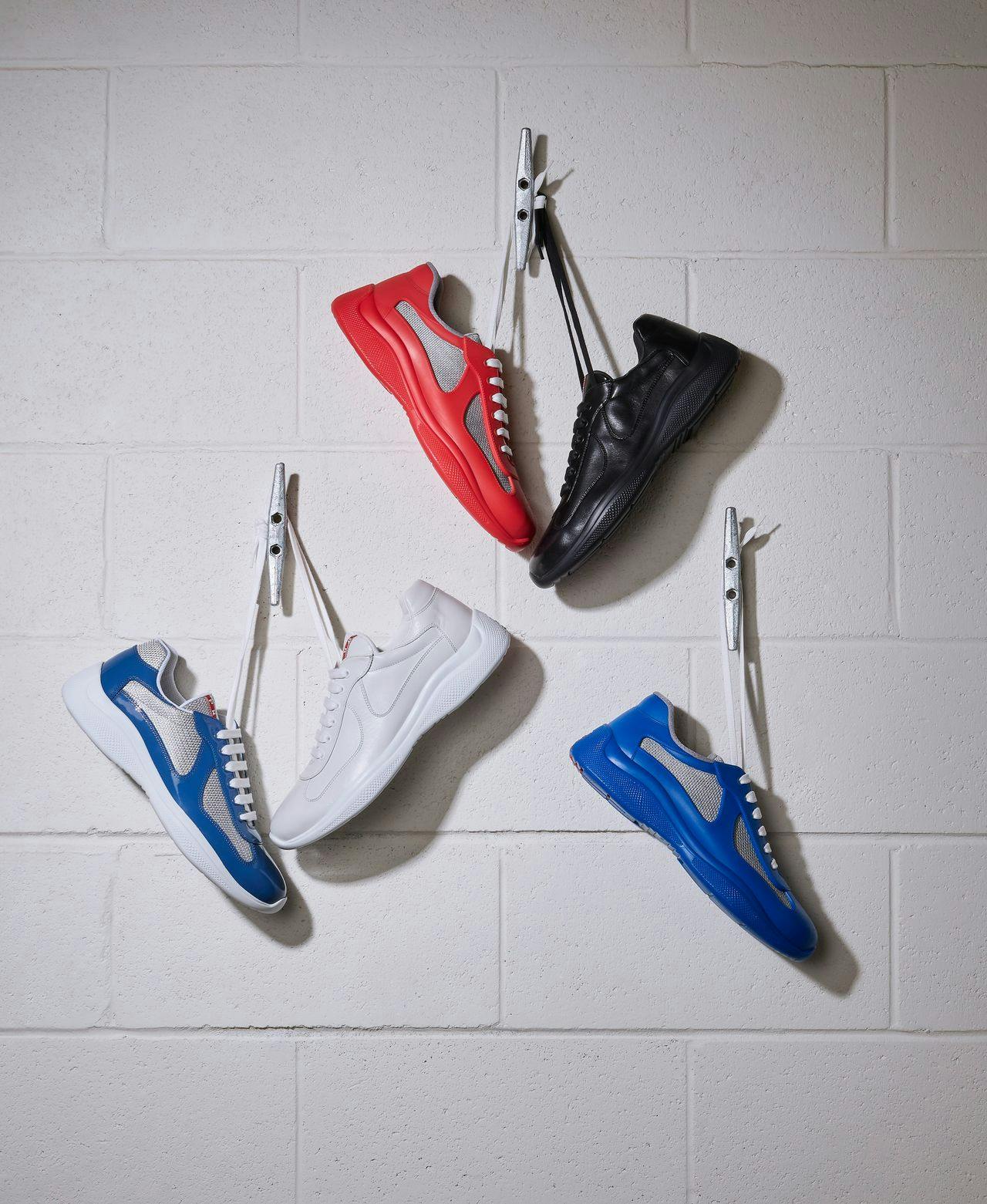 deux paires de baskets suspendues par des lacets sur un crochet au mur et une sneaker suspendue par des lacets sur un crochet au mur