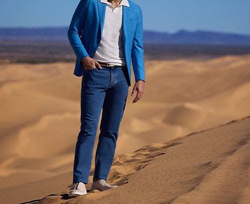 A man in a blue jacket standing on a desert