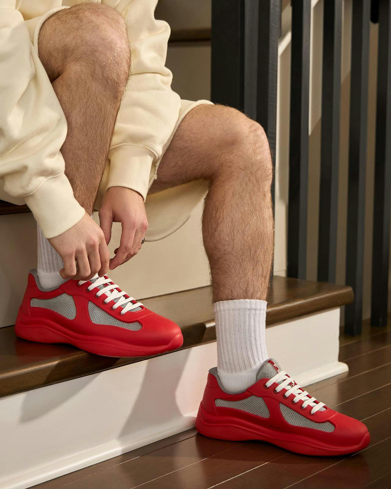 a man wearing red prada shoes tying his shoes
