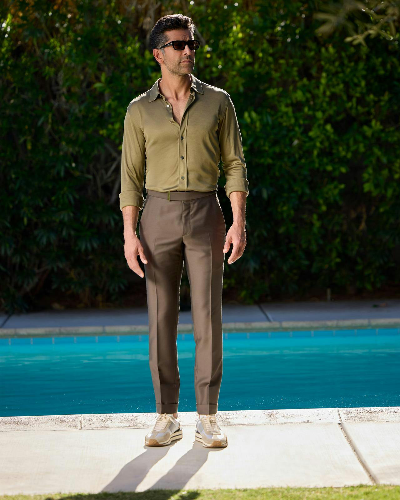 a man in a green shirt and pants standing in front of a pool