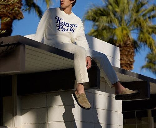 a man sitting on top of a building wearing a white kenzo sweatshirt