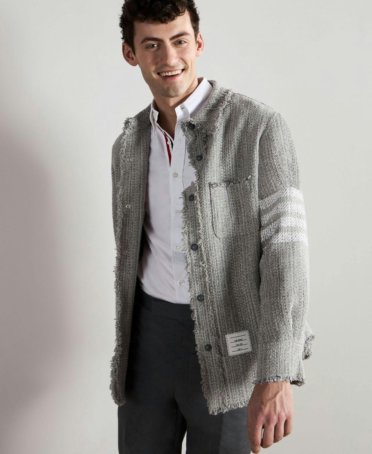 un homme dans une veste et un pantalon gris souriant