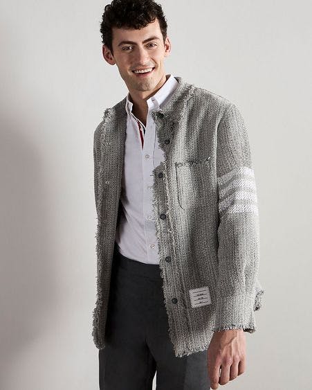 un homme dans une veste et un pantalon gris souriant