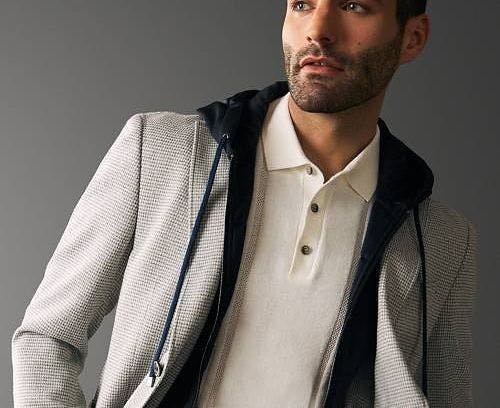 a guy wearing a polo and a sports jacket against a grey background