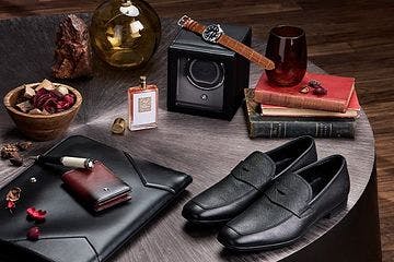 a table with a pair of shoes, a watch, a wallet, and a pair of glasses
