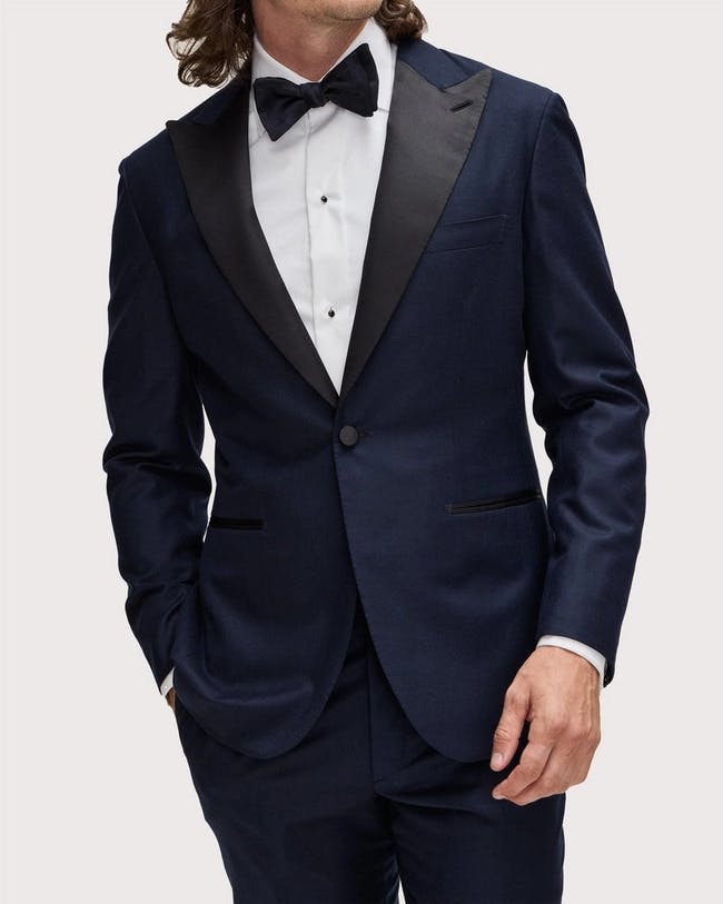 Brioni male model donning navy blue virgin wool tuxedo with bowtie.